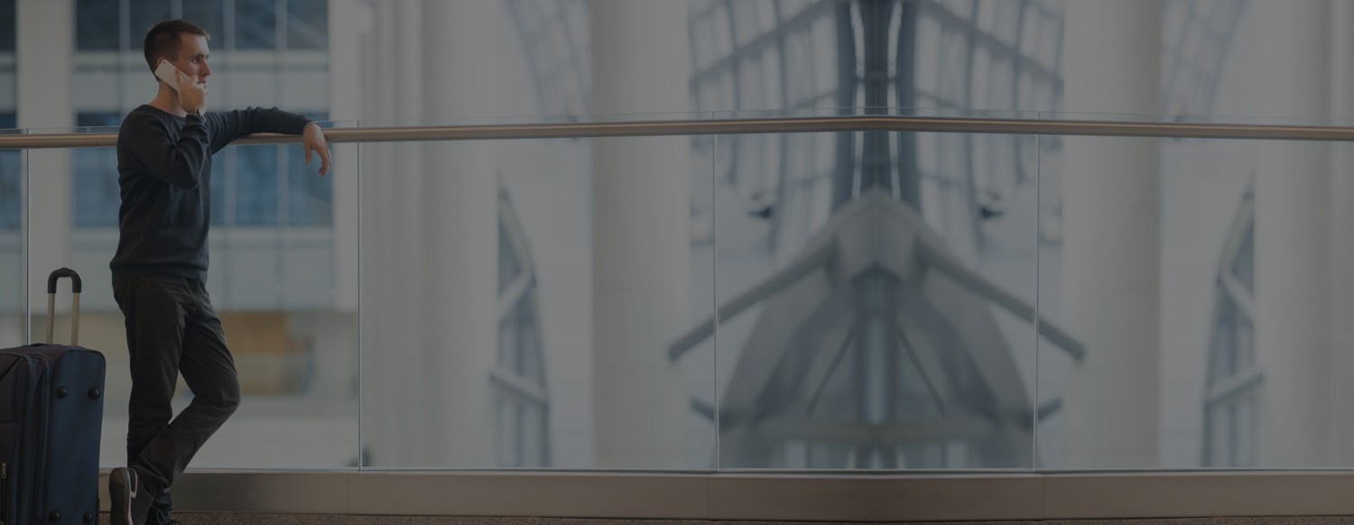Man talking on phone at airport terminal booking Blue Shuttle Van